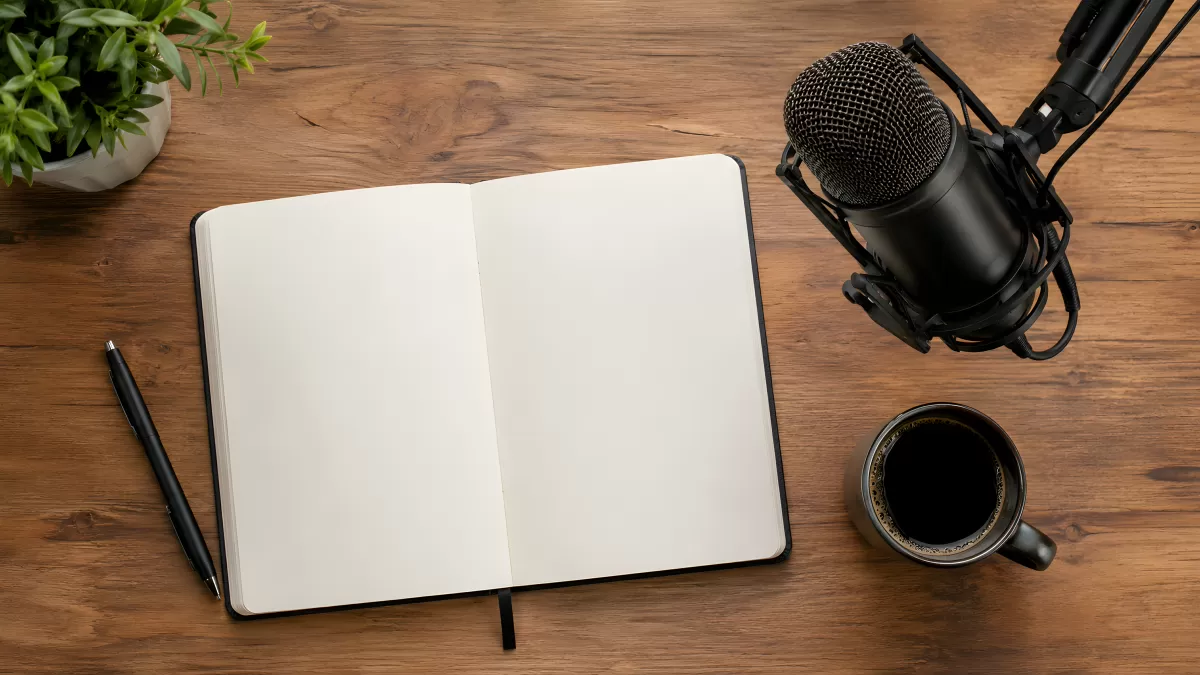 Podcast-Arbeitsplatz mit Mikrofon, Notizbuch und Kaffee