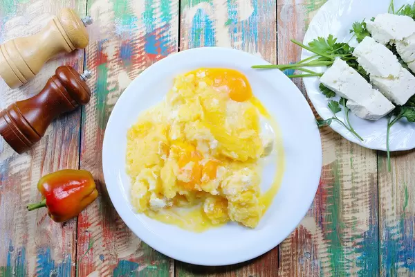 Polenta mit Käse, Sahne und Petersilie. Hölzerner Hintergrund im Vintage-Stil