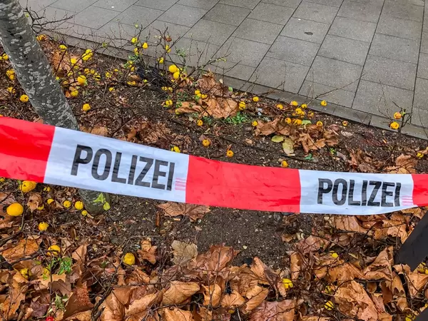 Polizei-Absperrband über kleiner Grünfläche vor Fussweg