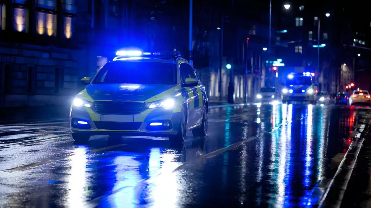 Polizeiauto mit Blaulicht auf nasser Stadtstraße bei Nacht