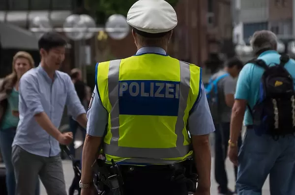Polizist mit Warnweste und Hut in einer Fußgängerzone