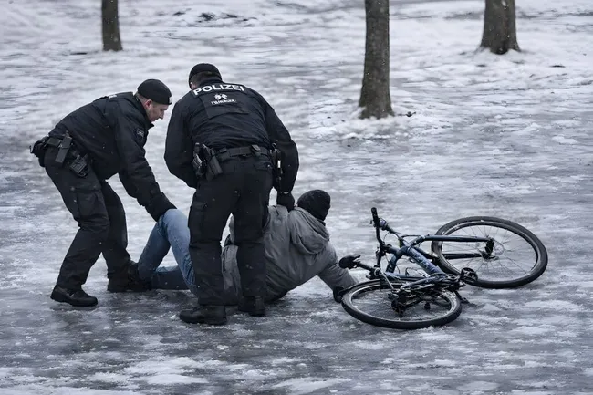 Polizisten helfen verletztem Radfahrer auf vereister Straße