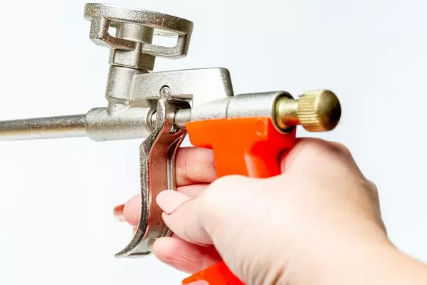 Polyurethane gun in hand on white (Flip 2020)