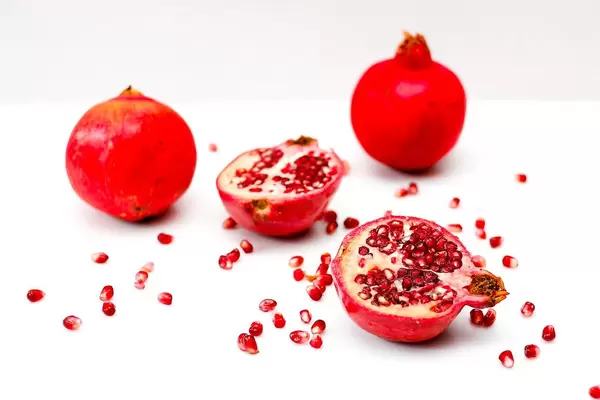 Pomegranate with red seeds on white surface