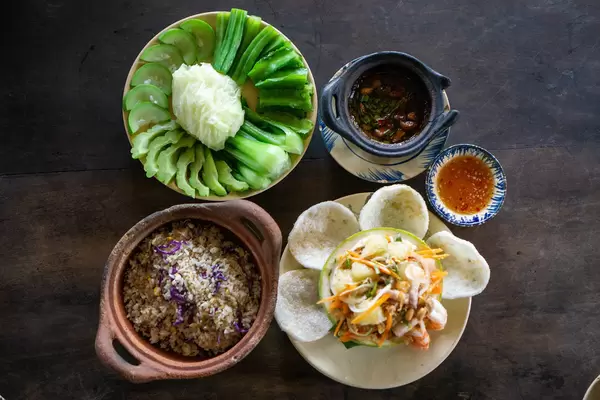 Pomelo Salad with Shrimp Chips, Fried Rice with Fish and Cooked Vegetables with Stew Pork Dip on a Wooden Table from above