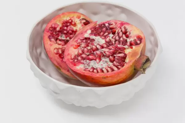Pommegranate halfs in white bowl on white background