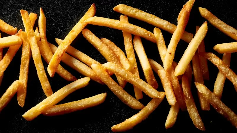 Pommes auf schwarzem Hintergrund mit knuspriger Textur