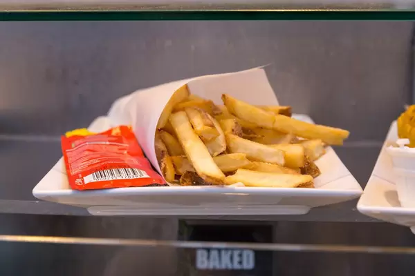 Pommes mit Ketchup-Tütchen auf einem Teller