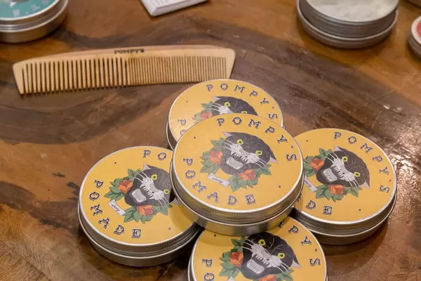 Pompy’s Haarpomade in Aluminiumdose mit hölzernem Kamm auf Holztisch