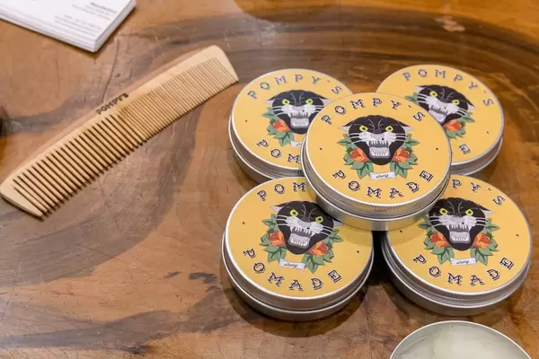 Pompy's hair pomade in aluminum can with wooden comb on wooden table