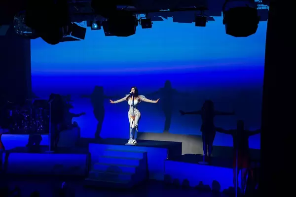 Pop star Marina on the stage in the spotlight with blue background