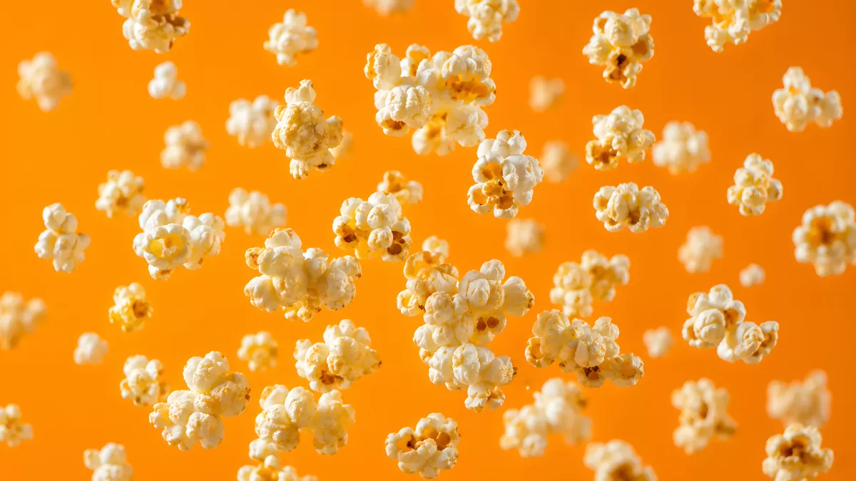 Popcorn fliegt durch die Luft vor orangem Hintergrund