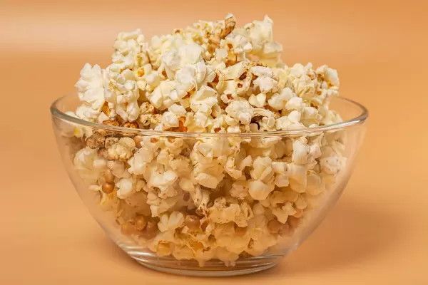 Popcorn in glass bowl on orange background