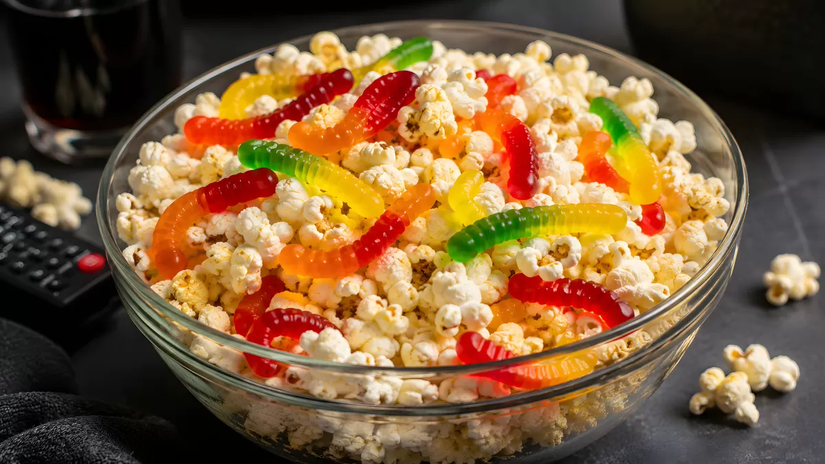 Popcorn mit bunten Gummiwürmern in Glasschüssel