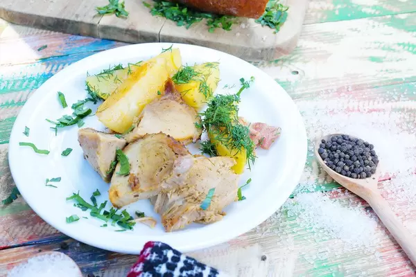 Pork roast with wedges on a  white plate. Salt and pepper on a vintage wooden background (Flip 2019)