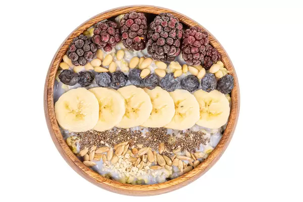 Porridge with different seeds, blackberry, banana, blackthorn and nuts on white, top view