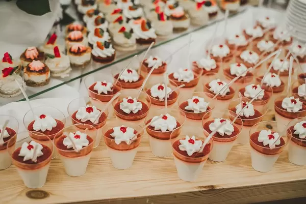Portionen an Panna Cotta mit Erdbeeren und Sahnehäubchen in Plastikbecher