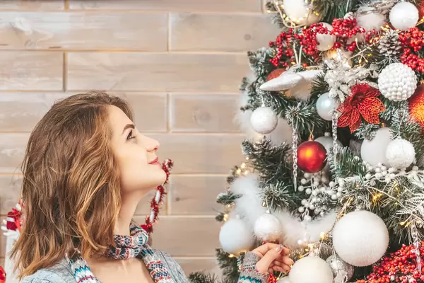 Portrait of a girl with a smile looks at the christmas tree