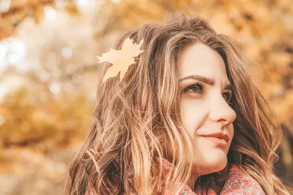 Portrait of a young girl with an autumn maple leaf in her hair