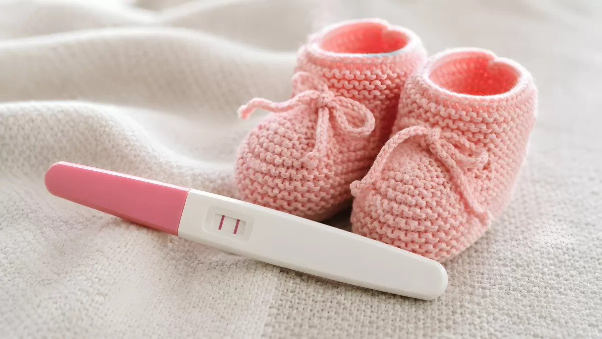 Positiver Schwangerschaftstest mit rosa Babyschuhen