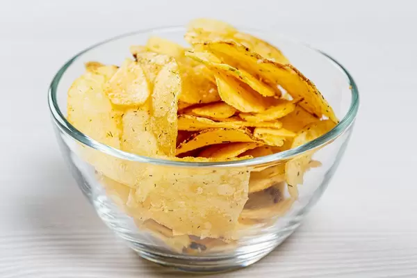 Potato chips in a glass bowl on a white table