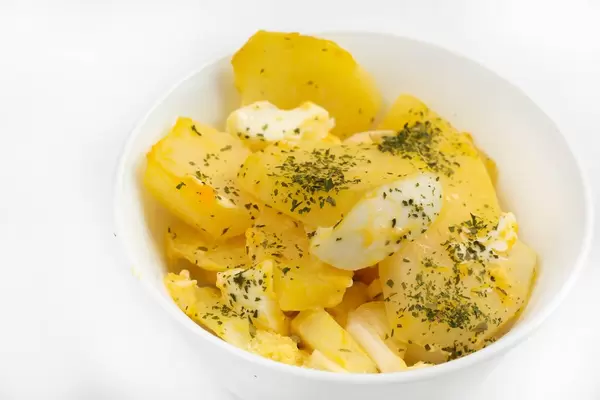 Potatoe salad with Eggs and Onions in white bowl
