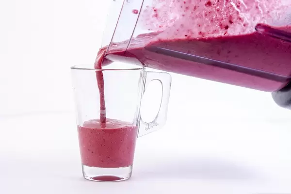 Pouring Raspberry Banana and Blackberry Smoothie in the glass