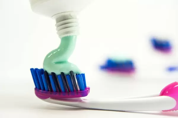 Pouring toothpaste on a toothbursh