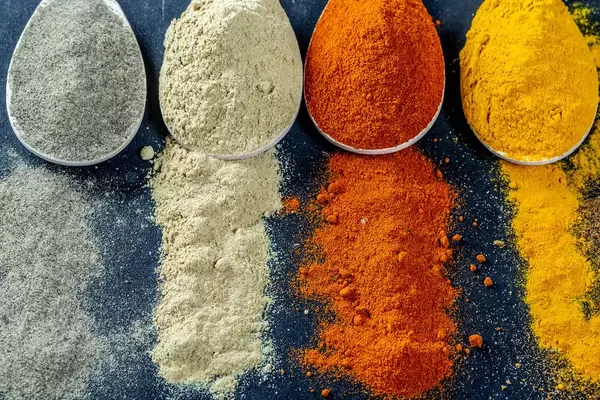 Powder multi-colored spices scattered and in wooden spoons