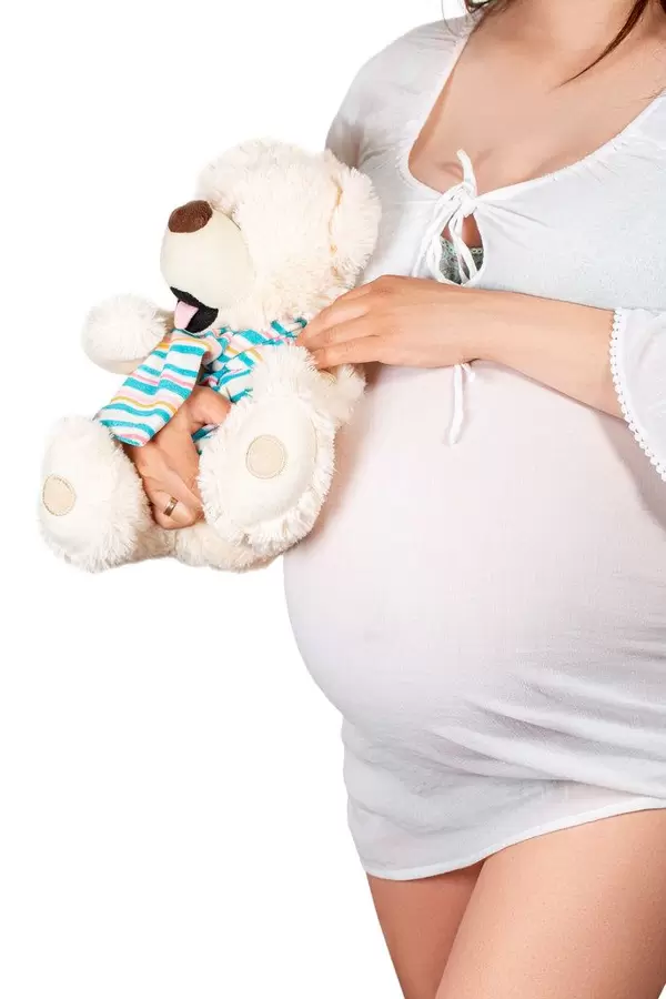 Pregnant girl hugs bear soft toy