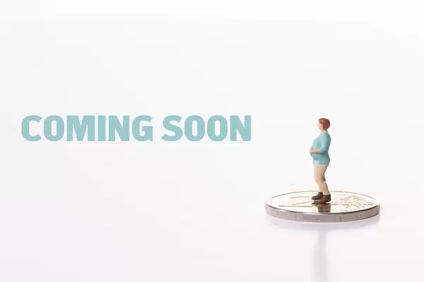 Pregnant woman standing on 2 Euro coin with Coming Soon text