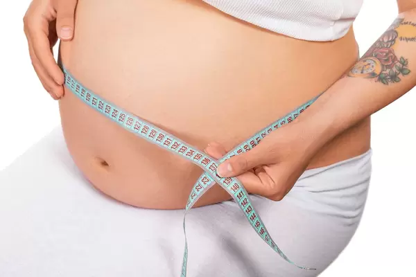 Pregnant woman with measuring tape measures her girth