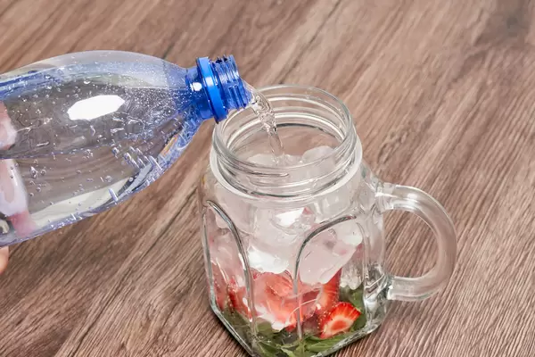 Preparing cold summer drink with fruits and soda