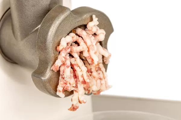 Process of meat grinding in the kitchen with mincing machine, close up