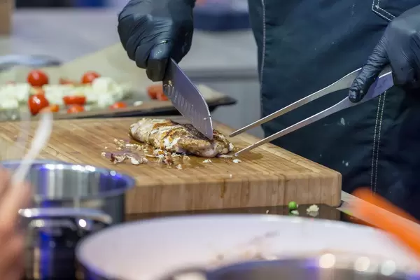 Professional chef chopping grilled meat on a cutting board