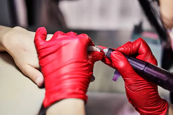 professional nail technician sanding nails with machine