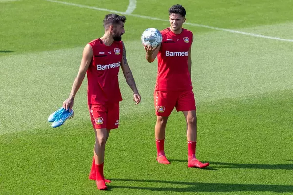 Professional soccer player Nadiem Amiri holding up a Derbster soccer ball, while talking to team member Kerem Demirbay