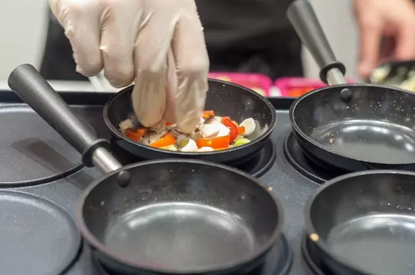 Profi-Koch bereitet Gemüsebeilage in kleiner Pfanne zu