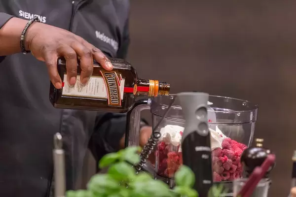 Profi-Koch gibt einen Schuss Cointreau zum Himbeereis hinzu