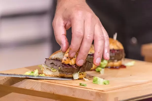 Profi-Koch schneidet einen Hamburger