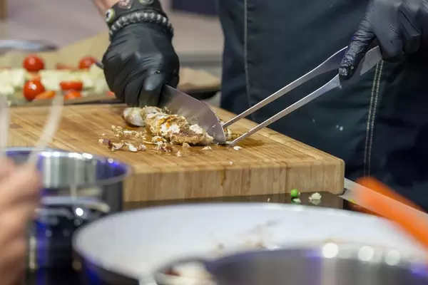 Profi-Koch zerkleinert gegrilltes Fleisch auf einem Küchenbrett