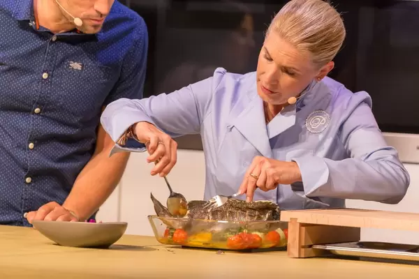 Profi-Köchin wendet den gebratenen Fisch