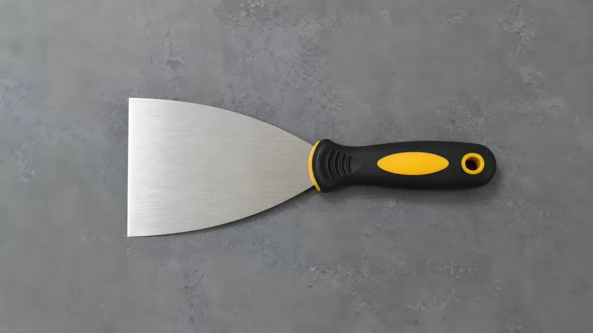 Profi-Spachtel mit schwarzgelbem Griff auf Betonuntergrund