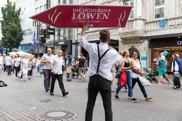 Promoter with a banner for the Pop-up-Store Die Höhle des Löwen