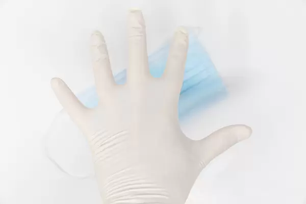 Protection from the second wave of Covid infections: hand with one-way glove and surgical face mask
