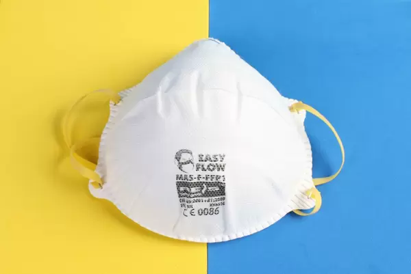 Protective face mask on yellow and blue background