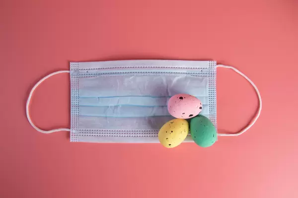 Protective face mask with Easter eggs on a pink background