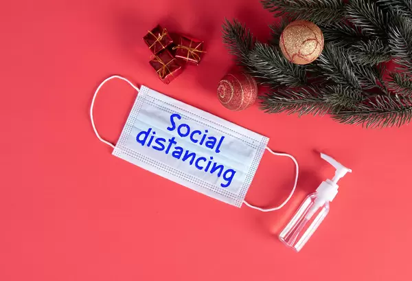 Protective face mask with Social Distancing text and Christmas decorations on red blue background