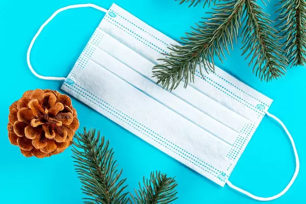 Protective mask, tree branches and a cone on a blue background