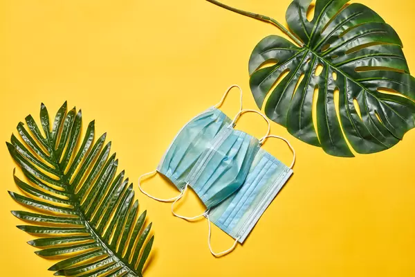 Protective medical masks on background with palm leaves